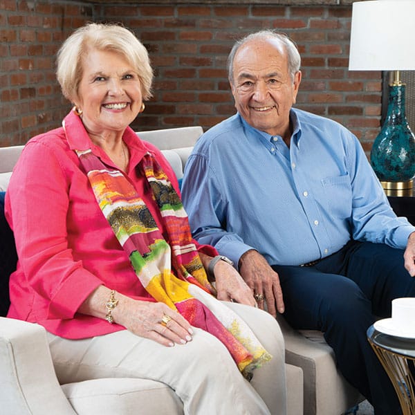 An older couple sitting on a couch with a cup of coffee.