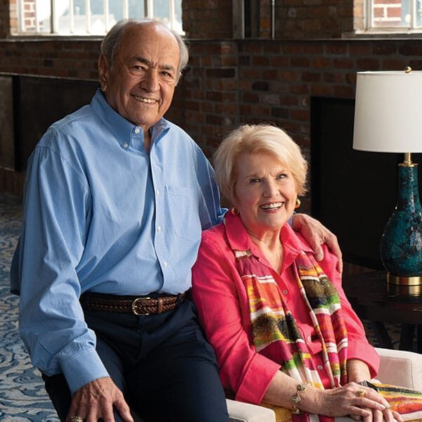 An older couple sitting on a chair in a living room.